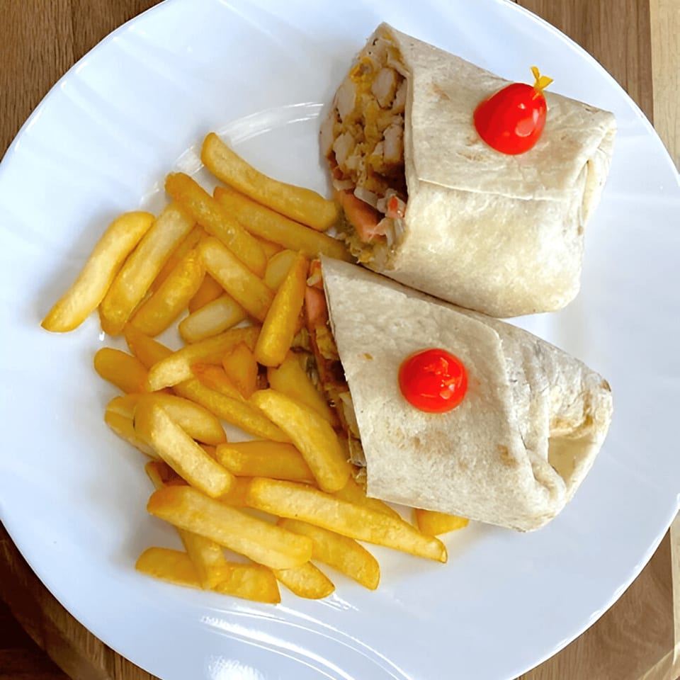 Two chicken wraps with red cherry tomato garnishes, served with golden french fries on a white plate.